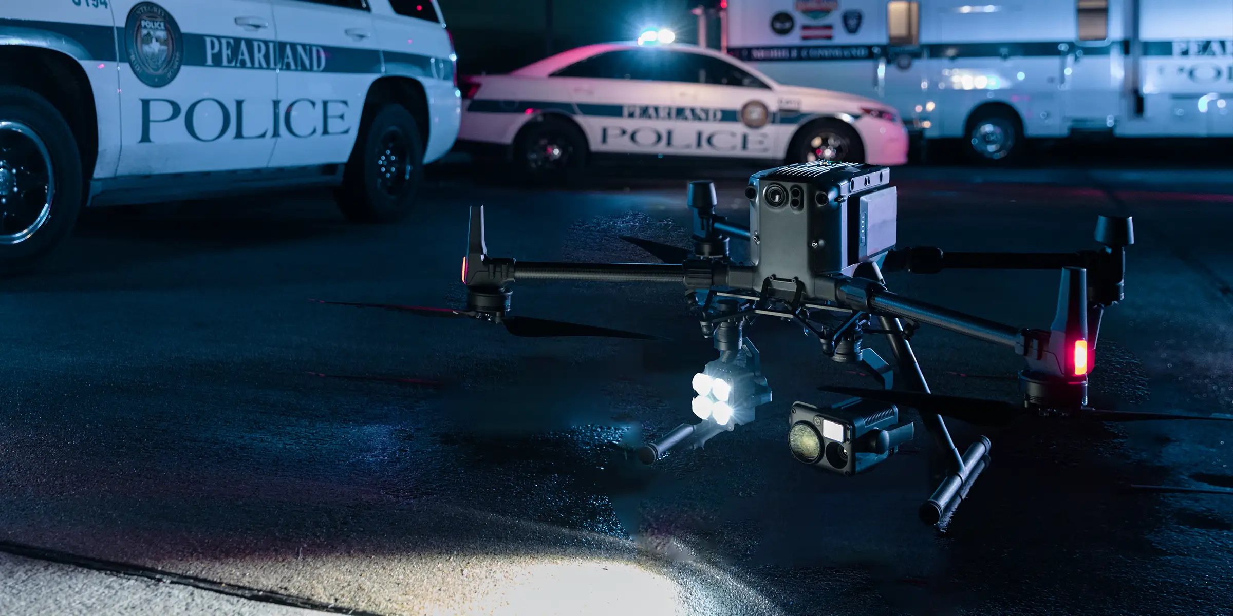 Public-safety drone staged beside police vehicles at night